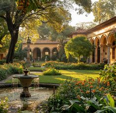 a fountain in the middle of a garden surrounded by trees and bushes with orange flowers