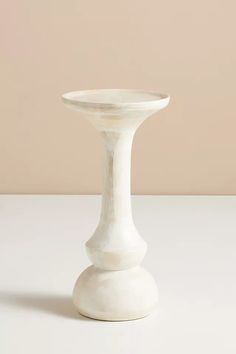 a white vase sitting on top of a table