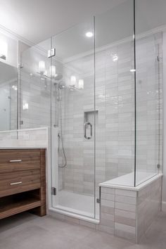 a bathroom with a walk in shower next to a sink and a wooden cabinet on the side