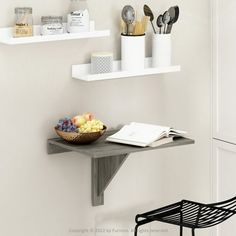 two white shelves with utensils and a bowl of fruit