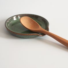 a wooden spoon in a green ceramic bowl