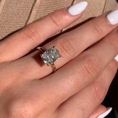 a woman's hand with white nails and an engagement ring