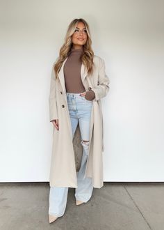 This Twill Trench Coat is the perfect balance of comfort and style, with professional lapel details and button closures that make a statement. The neutral hue and elevated design make this piece trendy and perfect for layering during the Fall in New York. Featuring a long silhouette, cozy fabric, and waist tie detail, you'll be reaching for this coat all season. Self 65% Polyester 35% Cotton Lining 100% Polyester Hand wash cold. Trendy Modest Fall Outfits, Fall Outfits Women Chicago, Trendy New York Outfits Winter, Winter Outfits Cold Trench Coat, Ivory Fall Outfits, Paris Outfits November 2024, Trench Coat Outfit Ideas For Women, Elevated Style Outfits, Boston Fashion Winter