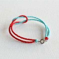 a red and blue beaded bracelet on a white surface