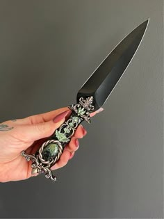 a person holding a knife with an ornate design on it's handle and blade