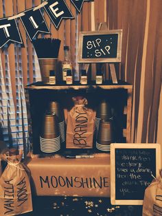 a table topped with lots of bottles and bags next to a sign that says moon shine