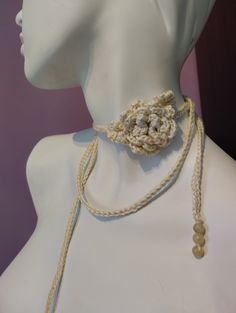 a white mannequin wearing a crochet flower on it's neck