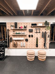 there are two stools in front of the pegboard with many items on it