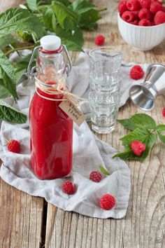 raspberry syrup in a glass jar with fresh raspberries on the side