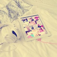 an ipad and headphones on a bed