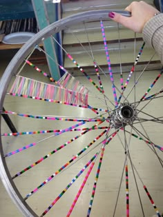 a person is holding a wheel with colored sticks attached to the spokes on it