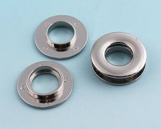 three stainless steel washers sitting next to each other on a blue surface with spacers in the middle