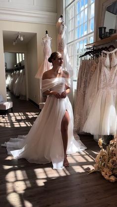 a woman in a white dress standing next to some dresses