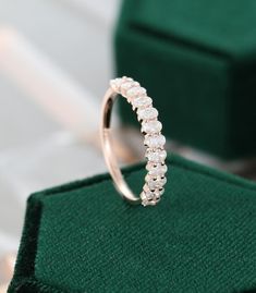 a diamond ring sitting on top of a green velvet pad with a box in the background