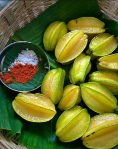 a basket filled with lots of fruit next to a pile of seasoning on top of a green leaf