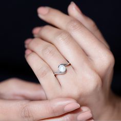 a woman's hand with a pearl ring on her left hand and the other hand holding it