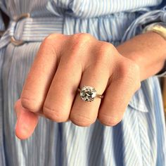 a close up of a person's hand with a ring on their finger, wearing a blue striped shirt