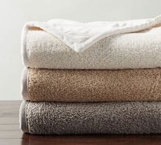 three towels stacked on top of each other in different colors and sizes, with one folded over the edge