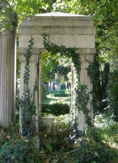 an old stone structure with vines growing on it's sides, surrounded by greenery