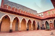 an old courtyard with stone arches and benches