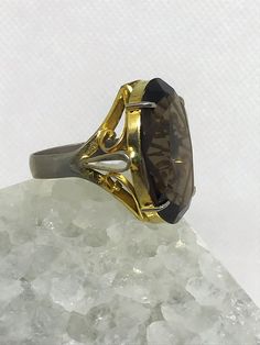 Beautiful large Smokey quartz cocktail ring. It features a gorgeous striking stone with a nicely detailed band. I'd estimate the age to be from the 1960's. Might be vermeil gold over silver as ring has some fading with gold. Ring does not have silver stamp. Size estimated to be an 8.5 to 9 woman's ring finger. Elegant Formal Topaz Ring With 17 Jewels, Gold Gemstone Rings For Evening, Emerald Cut Gemstone Rings For Evening, Oval Evening Rings With Center Stone, Classic Rings With Prong Setting For Evening, Classic Evening Rings With Prong Setting, Silver Gemstone Rings For Evening, Vintage Yellow Gold Rings For Evening, Elegant Formal Jewelry With Large Stone