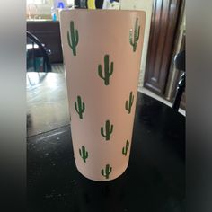 a cup with green cactus designs on it sitting on top of a black countertop