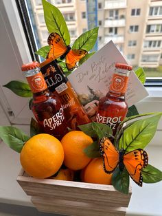 oranges and beer in a wooden box with butterflies on the window sill next to it