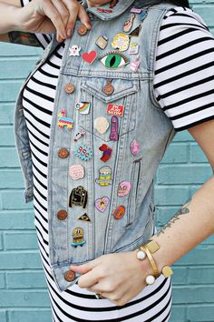 a woman wearing a denim vest with lots of patches on the front and back of it