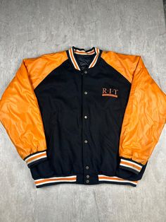 Show your school pride with our Steve & Barry's RIT Varsity Jacket. This jacket, in size 3XL, features the Rochester Institute of Technology emblem, offering both style and comfort for any RIT supporter or alumni. Please refer to the provided pictures for a detailed view of the condition and measurements of this item. We strive to present our pieces as accurately as possible, ensuring you have a clear understanding of their fit and wear. We put in our best efforts to clean and remove any stains, marks, etc. from our vintage pieces, but due to the nature of these items, some imperfections may remain. If you have any questions or require additional pictures, please don't hesitate to reach out to us! Collegiate Winter Outerwear For School, Collegiate Track Jacket With Letter Print For Fall, Collegiate Fall Track Jacket With Letter Print, Collegiate Style Track Jacket With Letter Print For Fall, Varsity Jacket For School In Fall, Collegiate Style Letter Print Track Jacket For Fall, Collegiate Outerwear For School In Fall, Retro Fall Outerwear For Campus, Winter School Spirit Outerwear For College