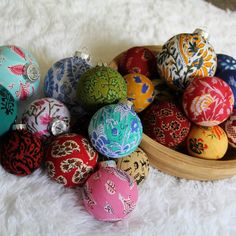 a wooden bowl filled with colorfully decorated eggs on top of a white carpeted floor