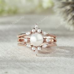 a pearl and diamond ring sitting on top of a table