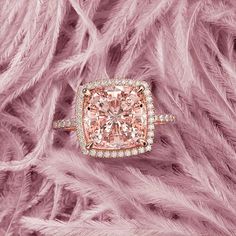 a pink diamond ring with diamonds on top and feathers in the background, all around it