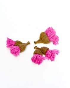 three pieces of pink and brown felt with tassels on white surface, top view