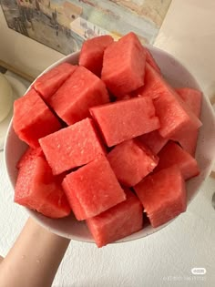 watermelon cubes in a white bowl being held by someone's hand