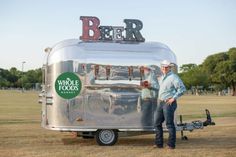 a man standing in front of a food truck with the word beer on it's roof