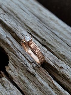 a close up of a ring on top of a piece of wood with a diamond in the middle