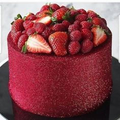 there is a red cake with strawberries on the top and bottom, decorated with glitter