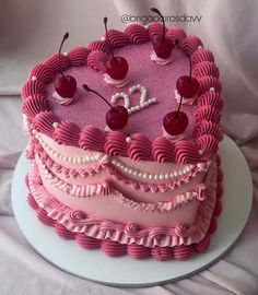 a pink cake with cherries on top and the number twenty five in the middle