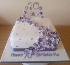 a birthday cake decorated with purple flowers and pearls