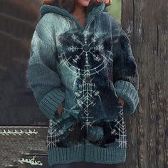 a woman standing next to a tree wearing a sweater