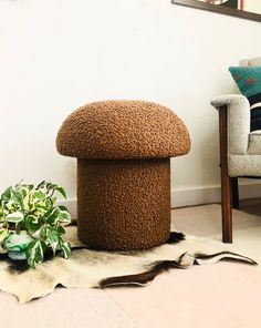 a brown ottoman sitting on top of a rug next to a chair and potted plant