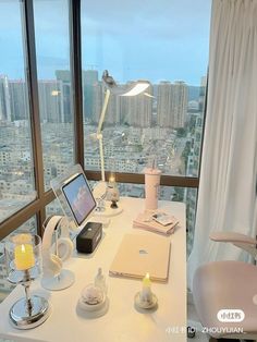 a desk with a laptop computer on top of it next to a window overlooking the city