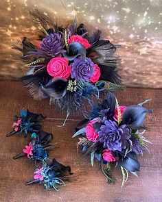 purple and pink flowers are arranged on a wooden table with feathers in the center for decoration