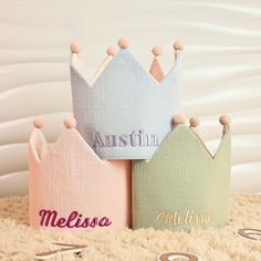 three little crowns with name on them sitting on a rug in front of a white wall