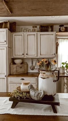 an old fashioned kitchen with white cabinets and flowers in a vase on the counter top