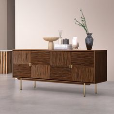 a sideboard with two vases on top of it next to a plant and other items