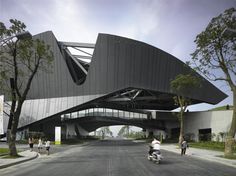 people are riding bikes in front of a large building that has a triangular design on it