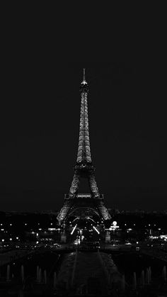 the eiffel tower lit up at night in black and white with its lights on