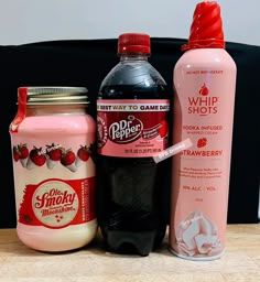 three different types of drink sitting on a table next to each other, one pink and one red