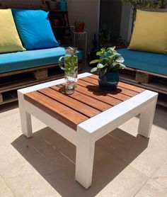 a wooden table sitting on top of a patio next to two couches and a potted plant